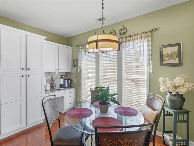 dining area featuring wood finished floors, visible vents, and an inviting chandelier