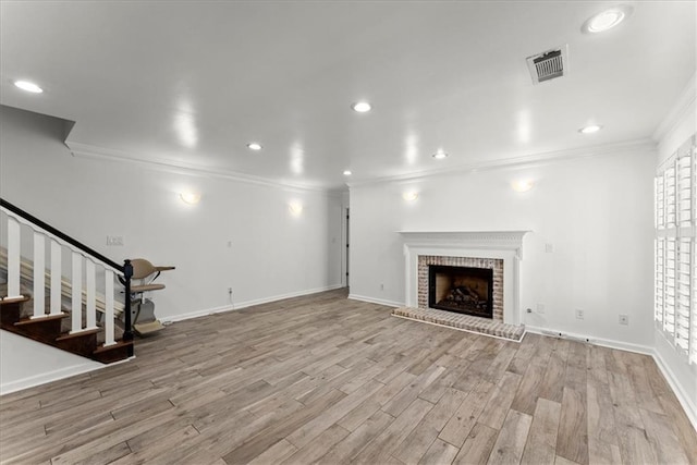 unfurnished living room with ornamental molding, a fireplace, light hardwood / wood-style floors, and a wealth of natural light