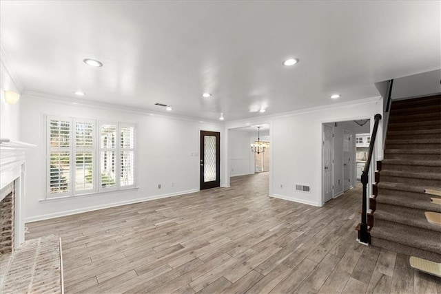 unfurnished living room with a notable chandelier, ornamental molding, and light wood-type flooring