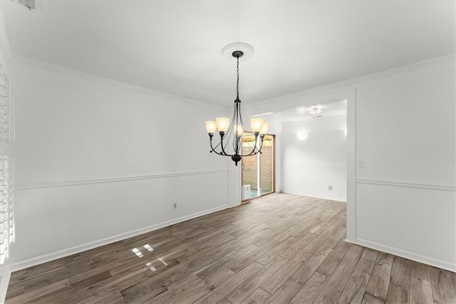 unfurnished dining area featuring crown molding, wood-type flooring, and a chandelier