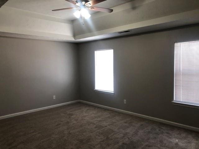 carpeted empty room with a tray ceiling and ceiling fan