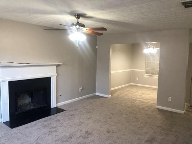 unfurnished living room with ceiling fan, carpet floors, and a textured ceiling