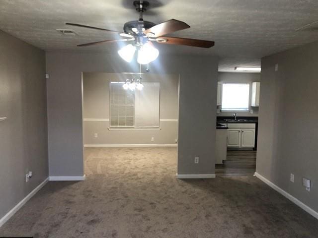 carpeted empty room with ceiling fan, sink, and a textured ceiling