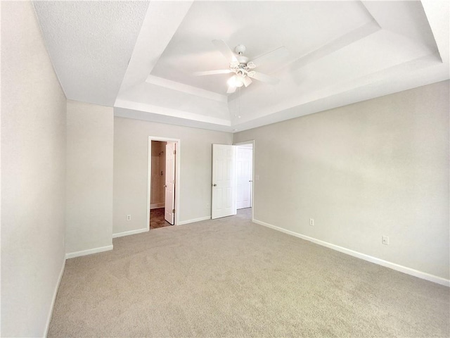 empty room with carpet, ceiling fan, and a tray ceiling