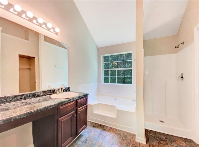 bathroom with shower with separate bathtub, vanity, and lofted ceiling