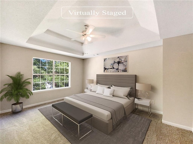 bedroom with carpet flooring, ceiling fan, a textured ceiling, and a tray ceiling