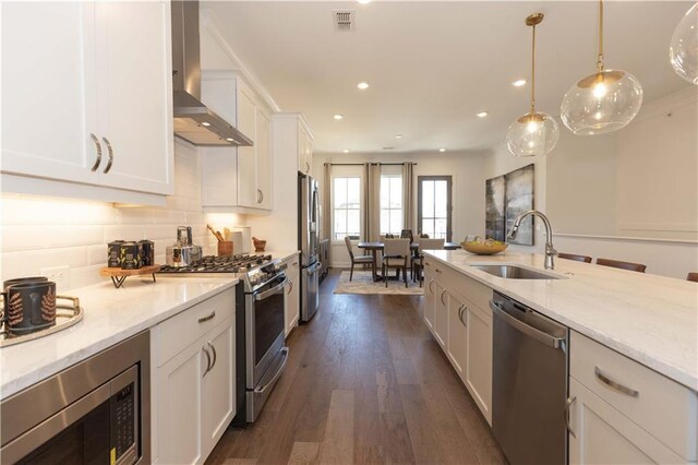 4923 Sudbrook Way Unit 233, Peachtree Corners, GA 30092 - kitchen featuring appliances with stainless steel finishes, wall chimney range hood, white cabinetry, light stone counters, and decorative light fixtures