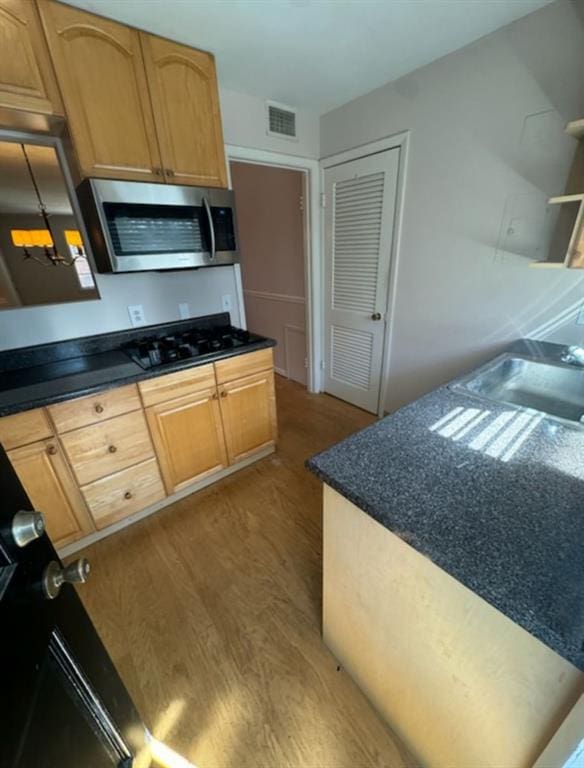 kitchen featuring sink, light brown cabinetry, light wood-type flooring, and black gas cooktop