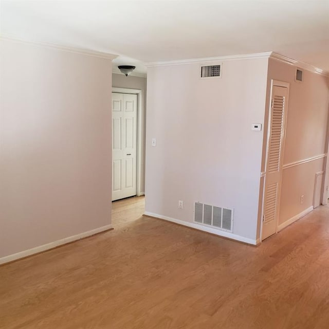 spare room featuring ornamental molding and light wood-type flooring