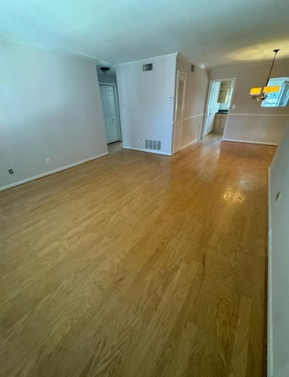 spare room with an inviting chandelier, wood-type flooring, and crown molding