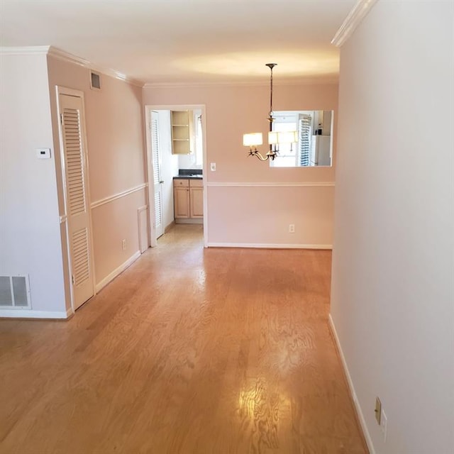 unfurnished dining area featuring a notable chandelier, hardwood / wood-style flooring, and ornamental molding