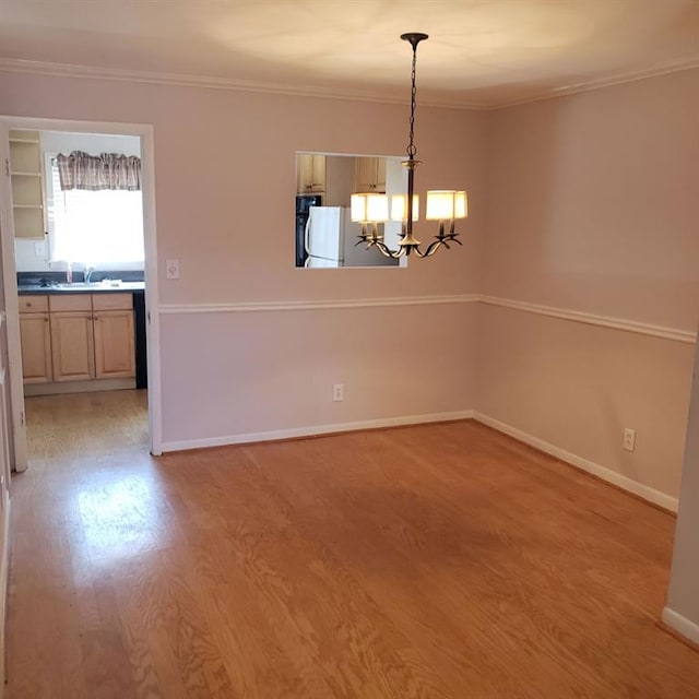 unfurnished dining area featuring ornamental molding, a chandelier, sink, and light hardwood / wood-style flooring