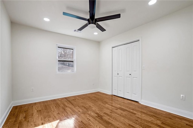 unfurnished bedroom with ceiling fan, a closet, and hardwood / wood-style flooring