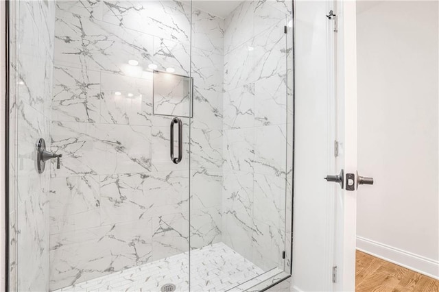 bathroom with a shower with shower door and hardwood / wood-style floors