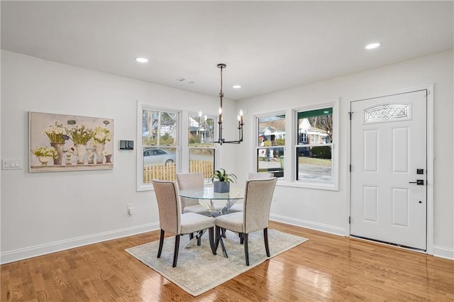 dining area with light wood-type flooring and a notable chandelier