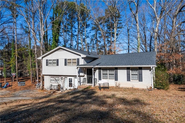 split level home with brick siding and roof with shingles