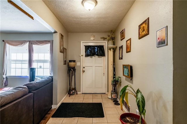 foyer with a textured ceiling, baseboards, and light tile patterned floors