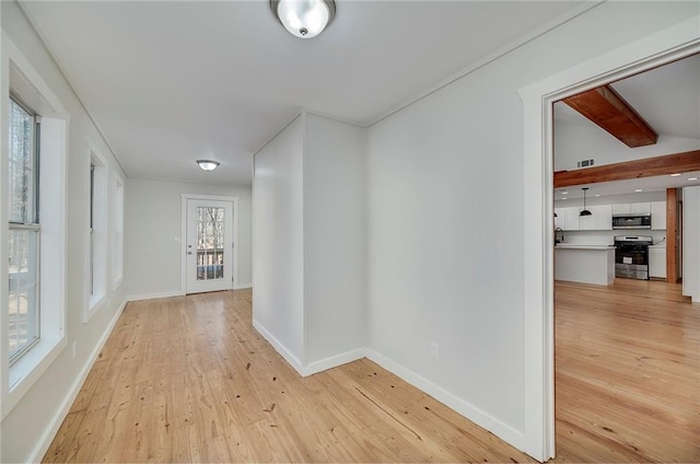 hallway featuring light wood-style flooring, visible vents, and baseboards