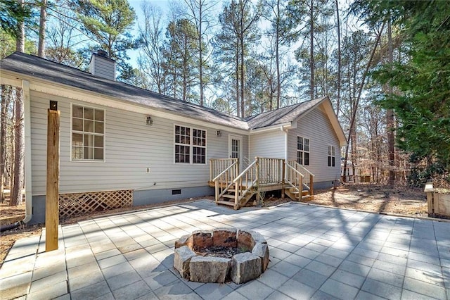 rear view of property featuring crawl space, a chimney, a fire pit, and a patio