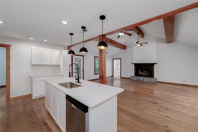 kitchen featuring decorative light fixtures, stainless steel dishwasher, open floor plan, white cabinetry, and an island with sink