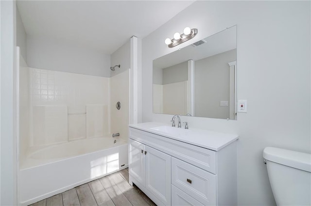 bathroom with wood finished floors, vanity, toilet, and shower / bathtub combination