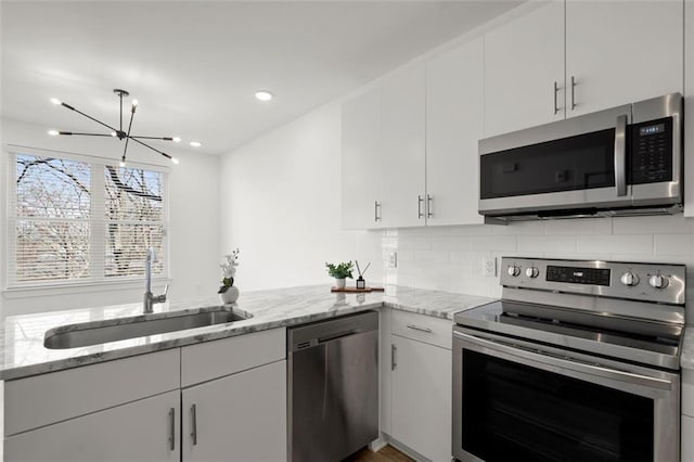 kitchen featuring decorative backsplash, white cabinetry, appliances with stainless steel finishes, and a sink