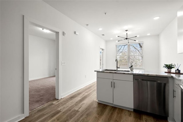 kitchen with light stone counters, dark wood-style floors, baseboards, a sink, and dishwasher