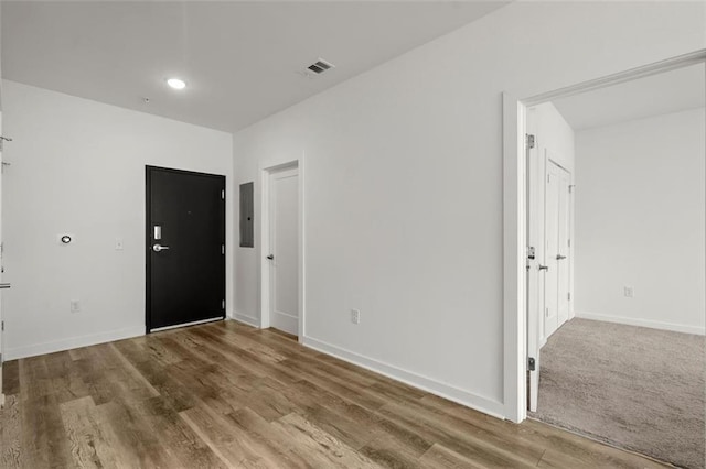 spare room featuring electric panel, wood finished floors, visible vents, and baseboards