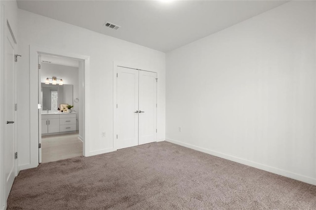 unfurnished bedroom with visible vents, carpet flooring, baseboards, and connected bathroom