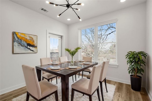 dining space featuring light wood-style flooring, baseboards, and visible vents