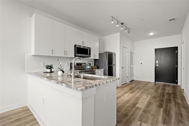 kitchen with visible vents, light wood-type flooring, decorative backsplash, appliances with stainless steel finishes, and a peninsula