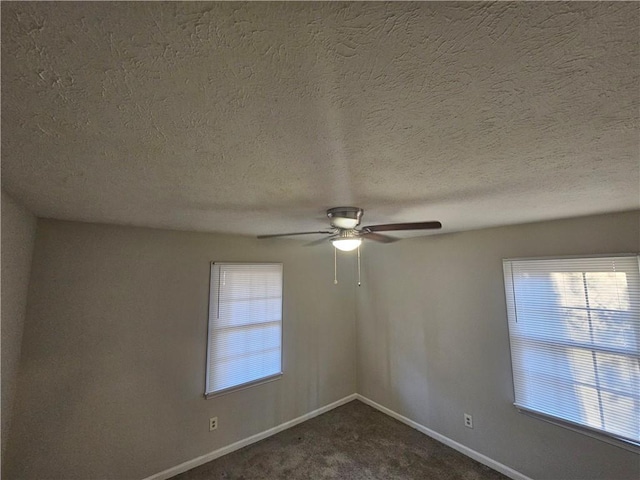 spare room with ceiling fan and dark colored carpet