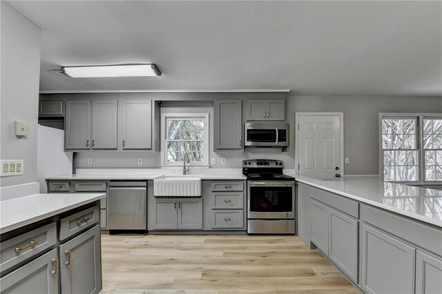 kitchen with kitchen peninsula, appliances with stainless steel finishes, gray cabinets, and plenty of natural light