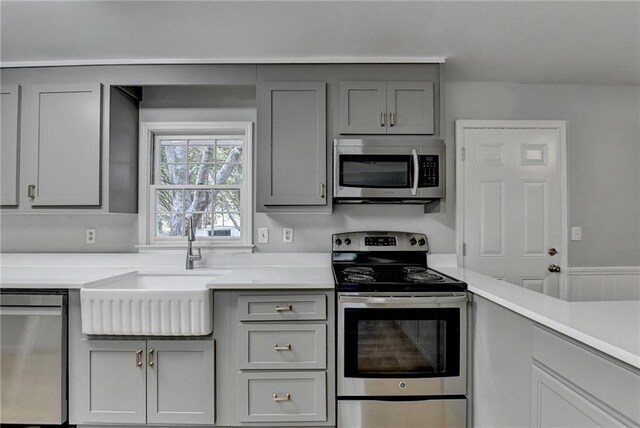 kitchen featuring appliances with stainless steel finishes, gray cabinets, and sink