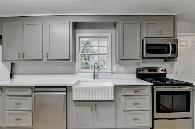 kitchen with appliances with stainless steel finishes, gray cabinetry, and sink