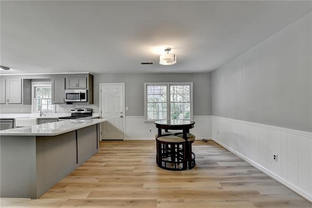 kitchen featuring stainless steel appliances, a kitchen island, gray cabinetry, and a breakfast bar area