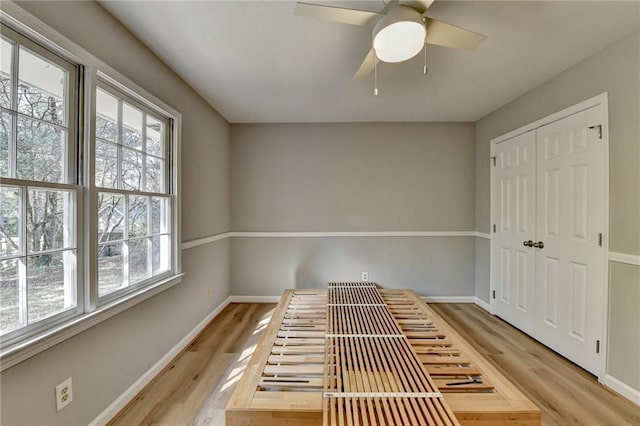 unfurnished bedroom with ceiling fan, a closet, and light wood-type flooring