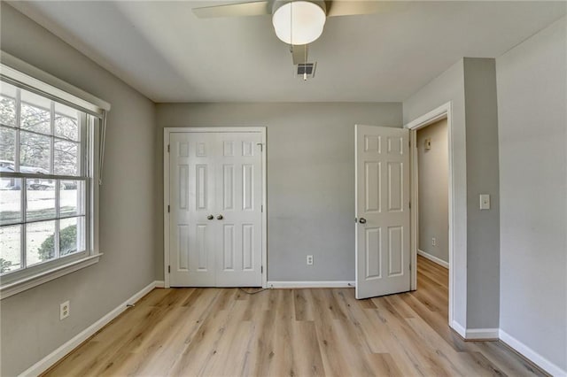 unfurnished bedroom with multiple windows, ceiling fan, a closet, and light hardwood / wood-style flooring