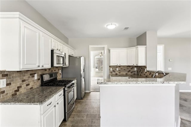 kitchen with visible vents, white cabinets, a peninsula, and stainless steel appliances