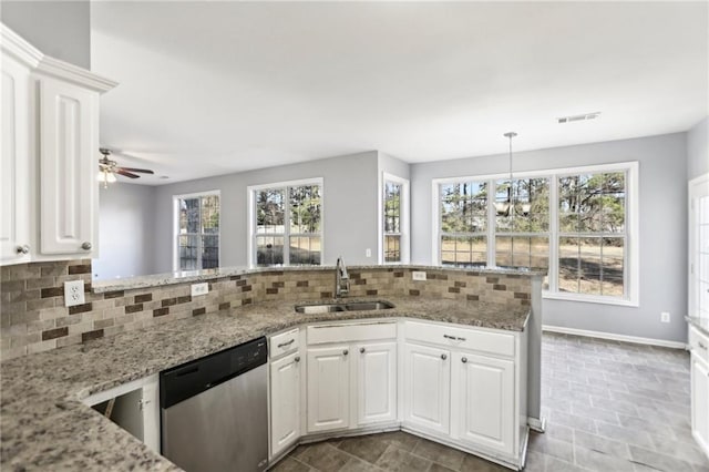 kitchen with light stone countertops, a sink, white cabinets, dishwasher, and backsplash