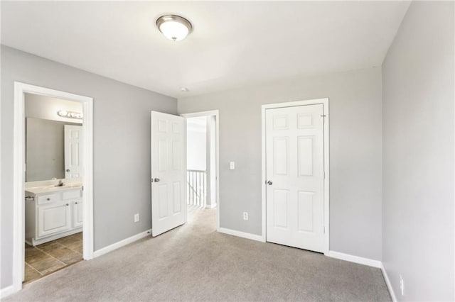 unfurnished bedroom featuring light colored carpet, baseboards, and ensuite bathroom