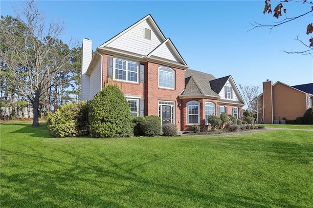 view of front of house with a front lawn, brick siding, and a chimney