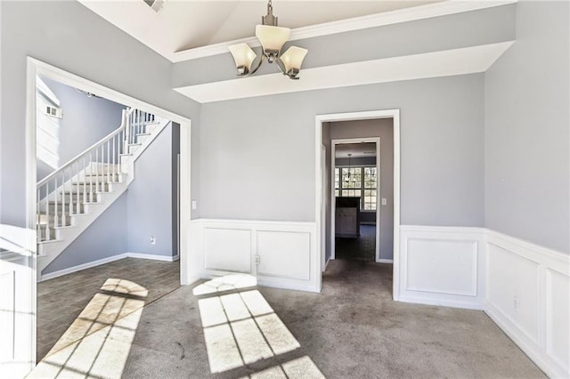 interior space with carpet, a chandelier, a wainscoted wall, stairs, and lofted ceiling