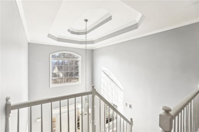 stairway featuring a raised ceiling, crown molding, and visible vents