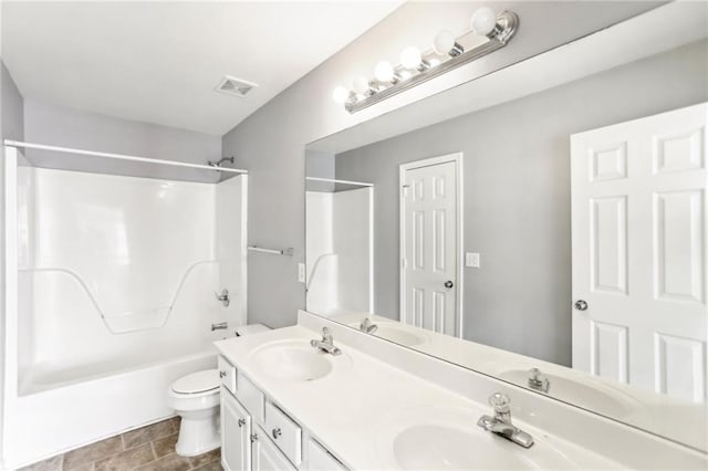 bathroom with double vanity, toilet, and a sink