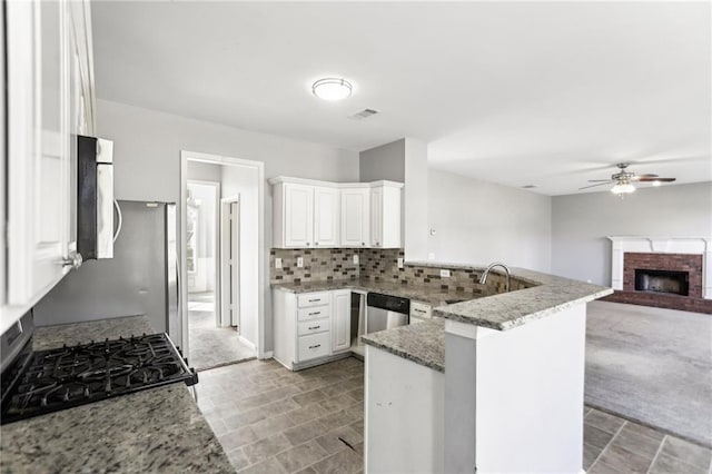 kitchen featuring light stone countertops, a peninsula, white cabinets, appliances with stainless steel finishes, and tasteful backsplash