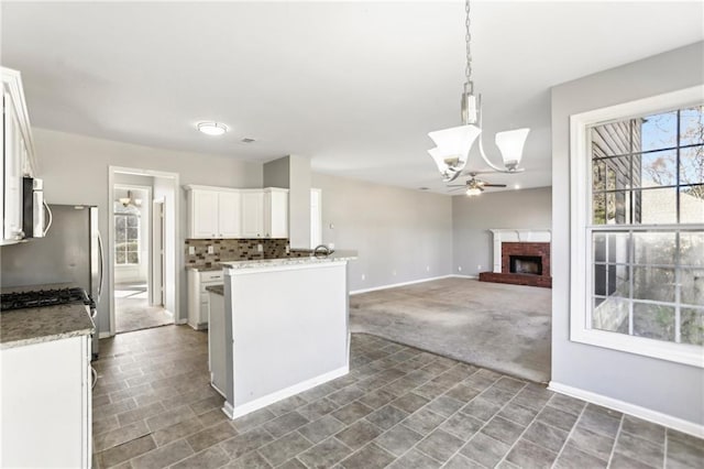 kitchen with a ceiling fan, carpet floors, decorative backsplash, white cabinetry, and stainless steel microwave