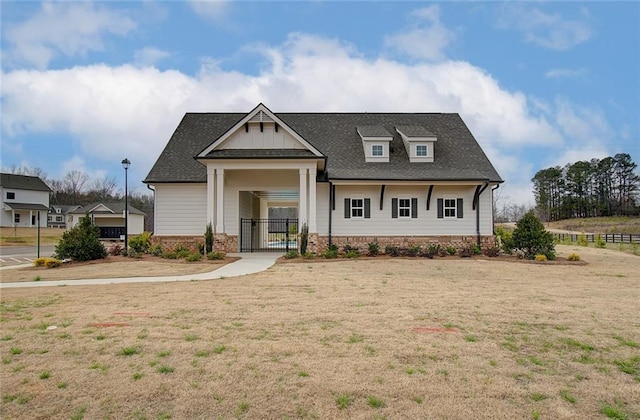 view of front of property featuring a shingled roof, a gate, and a front lawn