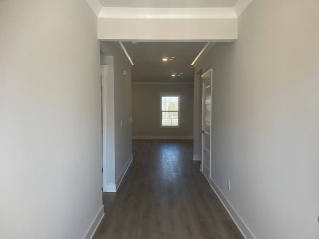 corridor featuring dark wood-style floors, baseboards, and ornamental molding