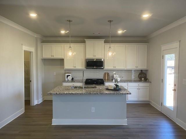 kitchen with stone countertops, stove, white cabinetry, backsplash, and stainless steel microwave